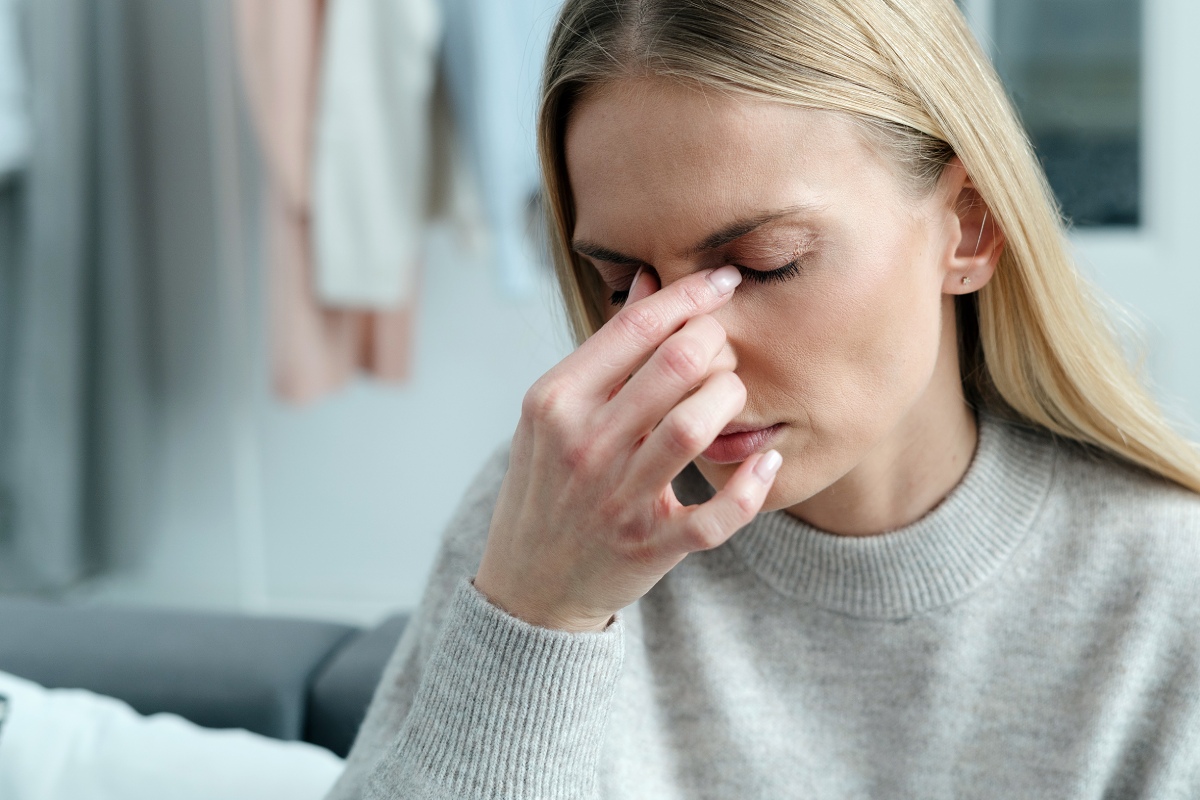 woman with eyes closed and touching face due to discomfort