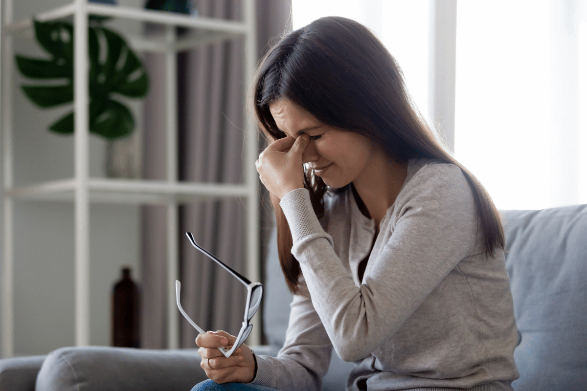 a woman taking off her glasses and looking uncomfortable